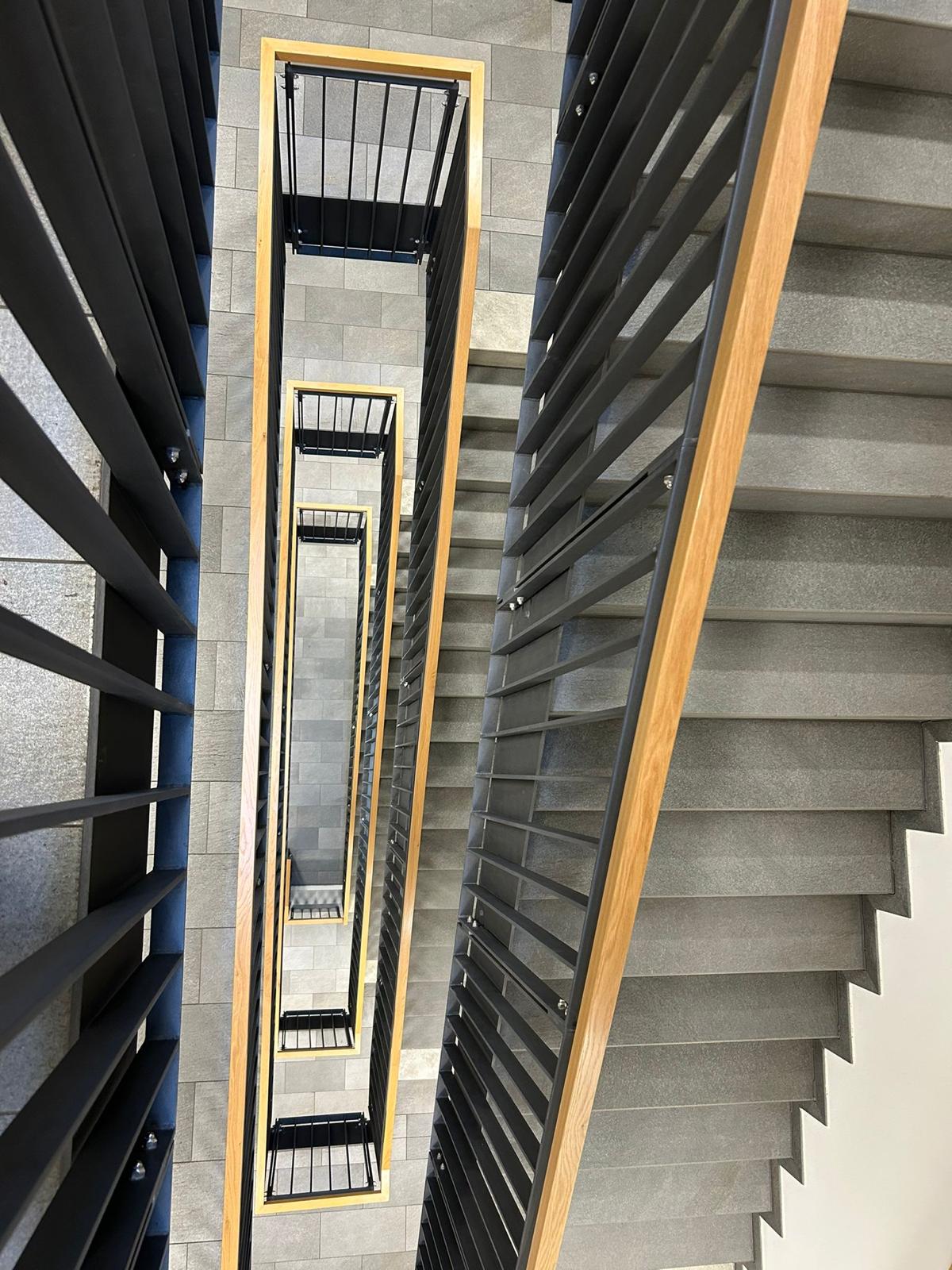 Moderne Treppenhaus-Architektur mit Betonstufen und Metallgeländern.