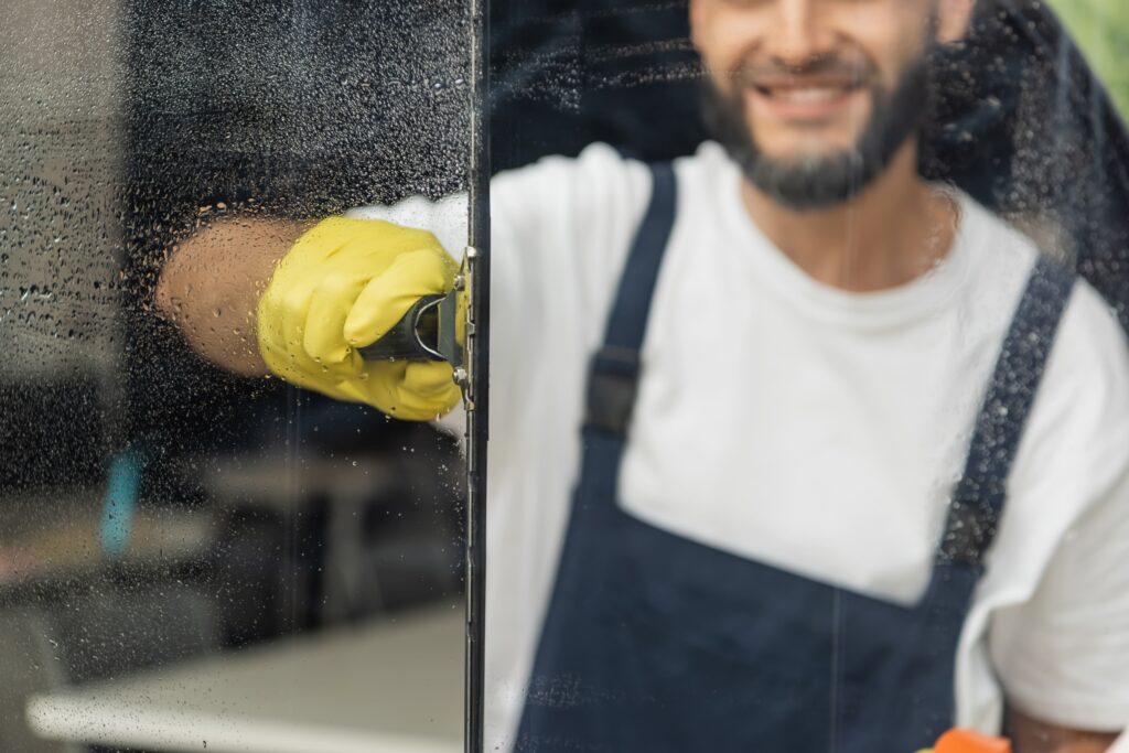 Mann mit gelben Handschuhen reinigt Fenster für Büroreinigung in Hannover.