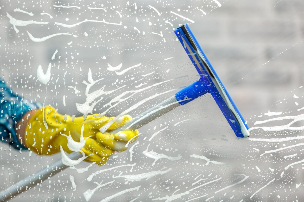 Fensterreinigung in Barsinghausen: Gelbe Handschuhe mit Abzieher auf Seifenfenster
