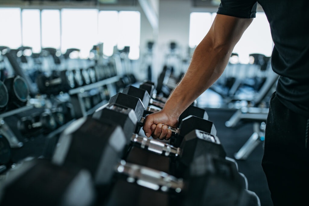 Fitnessstudioreinigung Hannover: Mann greift nach Hanteln