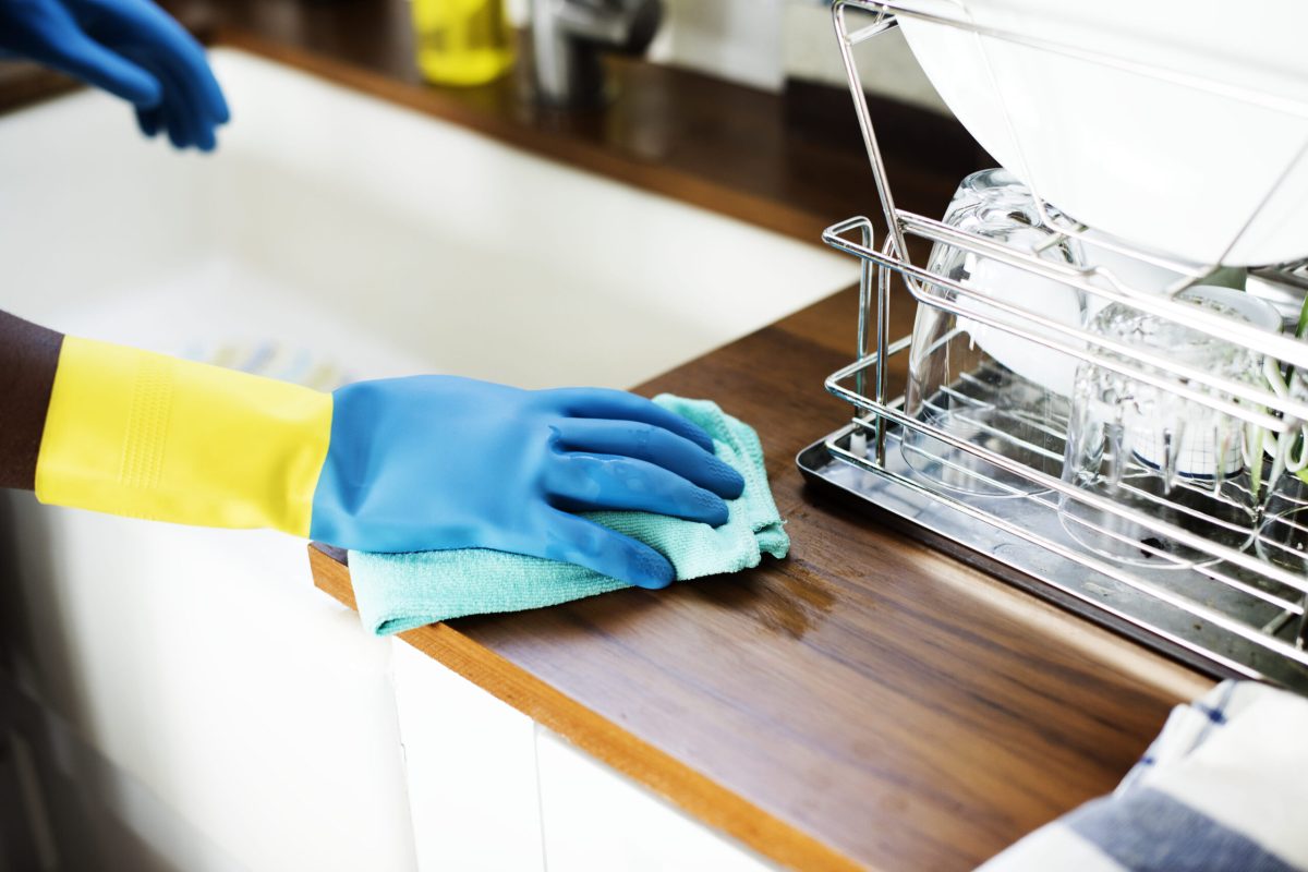 Reinigungshandschuhe reinigen Küche Arbeitsplatte mit grünem Tuch
